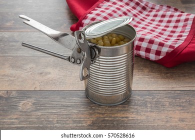 Old opener open to metallic can on the table in the kitchen. Canned corn in the can. Healthy eating and lifestyle.