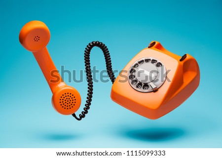 Old orange telephone rings with handset off.