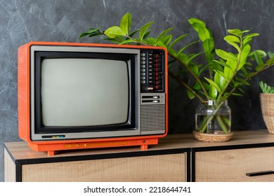 Old orange TV on a wooden cabinet in the room of the house. Loft wall. Warm atmosphere. vintage set of tv equipments concept. - Shutterstock ID 2218644741