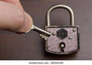 Old Padlock With Key On Dark Background