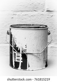 Old paint tin against painted brick wall. Black and white image.