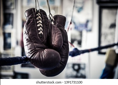 An Old Pair Of Boxing Gloves Hanging On The Ropes In A Boxing Gym Ring