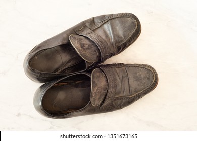 Old Pair Of Mens Black Dress Shoes That Are Worn Out, Very Dusty And Dirty And Falling Apart.  They Need Polish And Repair