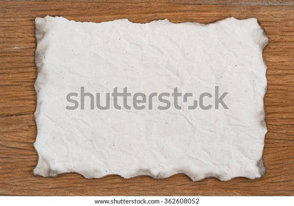 Old Paper\
with burned edges on wood\
background.