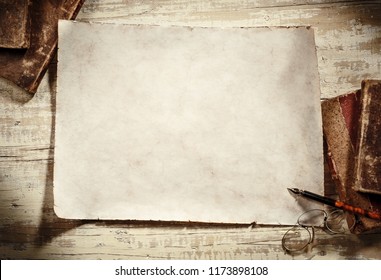 old parchment with books,spectacles and pen on antique writing desk