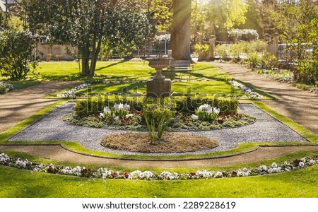 Old park in spring Dresden. Flowerbed with flowers and stone vase