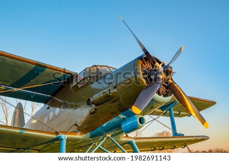 an old passenger military aircraft with a propeller and blades, from the time of the Second World War, stands in the airfield clearing against the blue sky