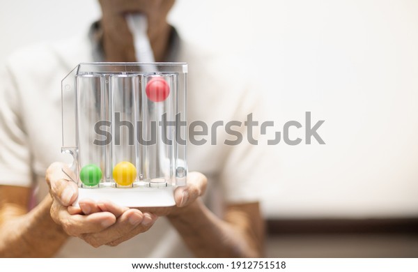 The old patient hand\
holding the Tri-ball incentive spirometry is medical equipment for\
post operation. The equipment for Lungs function testing and\
Pulmonary test.