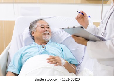 Alter Patient liegt im Krankenhausbett. Doktor, der Zwischenablage hält und zu ihm geht.