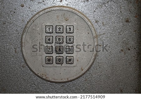 Old payphone dial with square buttons.