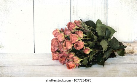 Old Peach Rose Bouquet With On A White Board Table And Against A Distressed Shiplap Board Background.  A Wide Horizontal Banner With Sepia Filter Tones And Has Some Grain Texture For A Vintage  Style