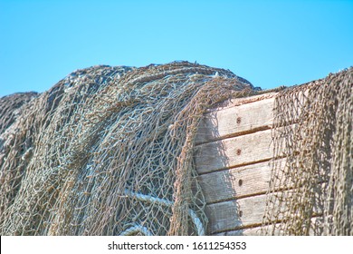 An old peeling fishing boat stands on the shore. A fishing net hangs on a boat. The texture of the old wood. - Powered by Shutterstock