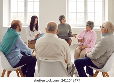 Old people communicating at group therapy meeting. Several male and female senior citizens sharing and talking about their concerns and problems at training workshop seminar with coach therapist - Powered by Shutterstock