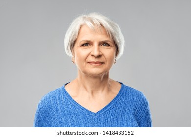 Old People Concept - Portrait Of Senior Woman In Blue Sweater Over Grey Background