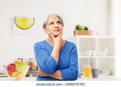 Old People And Decision Making Concept - Portrait Of Senior Woman In Blue Sweater Thinking Over Kitchen Background