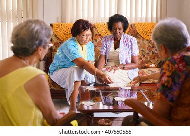 Old people in geriatric hospice: group of senior women playing cards and having fun together. The aged ladies sit on the sofa of the hospital and start a new match