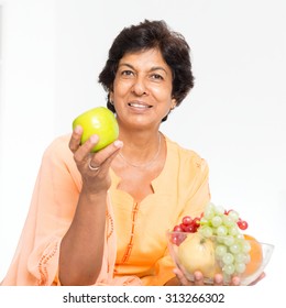 Old People Healthy Eating. Portrait Of A 50s Indian Mature Woman Eating Fruits At Home. Indoor Senior People Living Lifestyle.