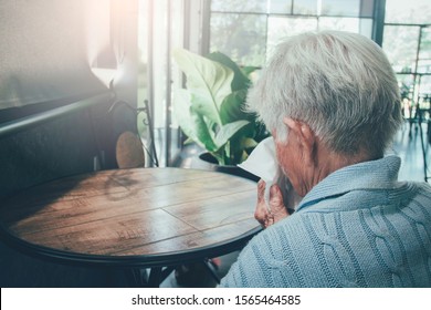 Old Person Coughing Covering Mouth With A Tissue On A House Interior. She Has Flu, Allergy Symptoms, Acute Bronchitis, Pulmonary Infections Or Pneumonia. Concept:respiratory Infections And Healthcare.