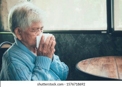 Old Person Coughing Covering Mouth With A Tissue On A House Interior. She Has Flu, Allergy Symptoms, Acute Bronchitis, Pulmonary Infections Or Pneumonia. Concept:respiratory Infections And Healthcare.