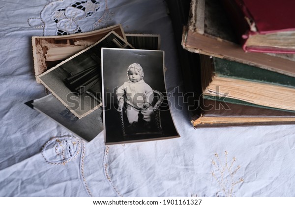 old photo albums lie on a white\
mint tablecloth, vintage photographs of 1960, concept of family\
tree, genealogy, childhood memories, connection with\
ancestors