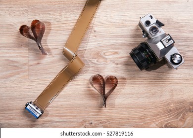 Old photo film, exposure meter and retro analog camera on wood background. Heart with photo film.