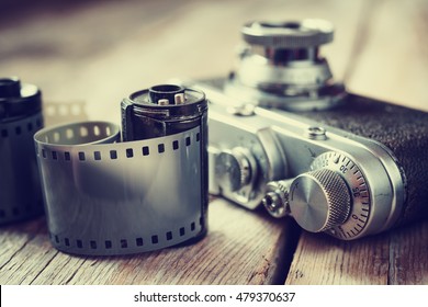 Old Photo Film Roll And Retro Camera On Desk.