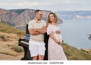 old piano, on against the backdrop of a rocky sea coast. a pregnant woman and a man stand next to him and look at each other