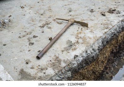 Old Pick Axe Placed On A Concrete Floor Surface After Digging For Drainage.