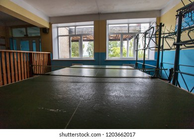 an old ping pong table stands in a poor school gym, a peeling lacquered finish and a broken racket-a joy for ghetto kids, a ball-kicking competition while playing table tennis, the best winner