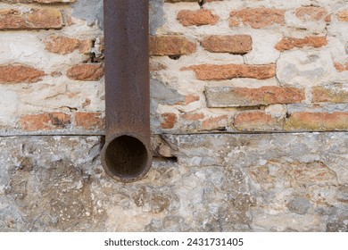 the old pipe of a gutter on a brick wall