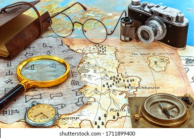 Old pirate and modern maps with a fragment of encrypted writing, a magnifying glass, an old camera, a compass and a pocket watch. Treasure hunting and archaeological research - Powered by Shutterstock