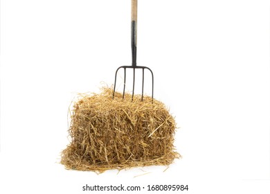 An Old Pitch Fork Stuck In A Straw Bale Isolated On White