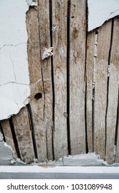 Old plaster breaks off exposing the wood beneath.
