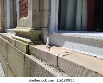 An Old Plastic Pipe Lying On A Windowsill To Get Rid Of Excess Water.