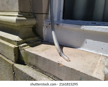 An Old Plastic Pipe Lying On A Windowsill To Get Rid Of Excess Water.