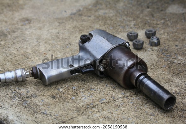 old pneumatic impact wrench and nuts on garage
concrete floor