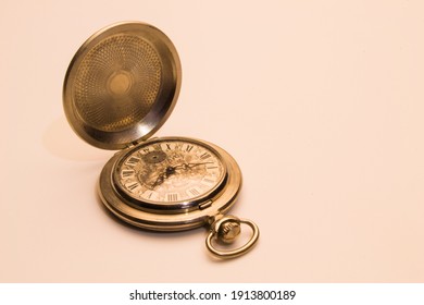 Old pocket watch inlaid with an open cover on a light background