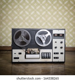 Old Portable Reel To Reel Tube Tape-recorder Is On Obsolete Parquet In Retro Room With Vintage Wallpaper. Toned