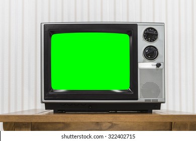 Old portable television set on vintage wood table with chroma key green screen.  