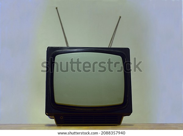 Old\
portable TV with antenna on a light\
background.
