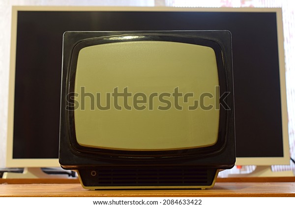 Old portable TV set against the background of a\
modern plasma TV.