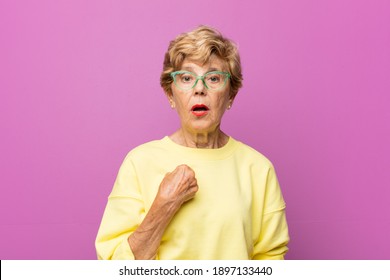 old pretty woman looking shocked and surprised with mouth wide open, pointing to self