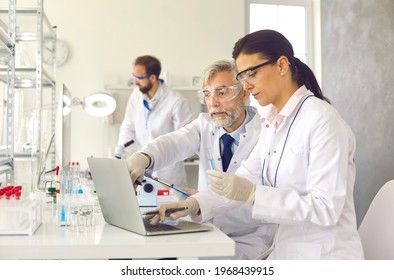 Old professor and young scientist with analysis sample working at laboratory discussing test result looking at on laptop screen. Chemistry research, new drug vaccine discovery concept - Powered by Shutterstock