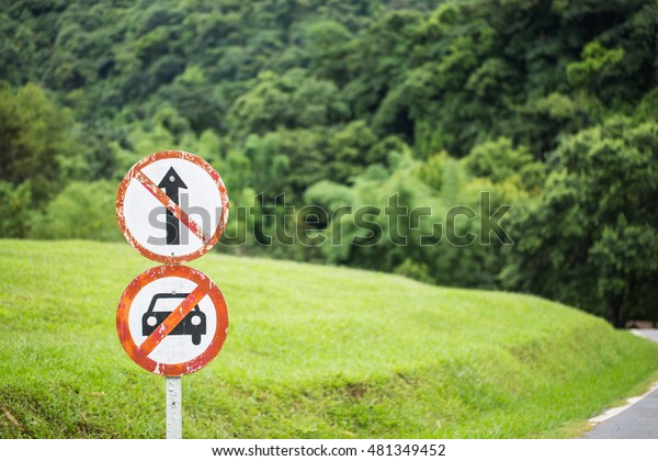 Old prohibited sign saying do not go\
straight and do not car allow in green grass\
nature