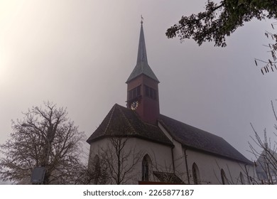 Old protestant church at hill of village Laufen-Uhwiesen on a foggy winter day. Photo taken February 16th, 2023, Laufen-Uhwiesen, Switzerland.