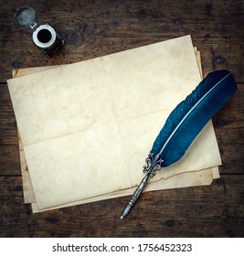 Old quill pen, and old paper blank sheet and vintage inkwell on wooden desk in the old office . Retro style. Conceptual background on history, education, literature topics.