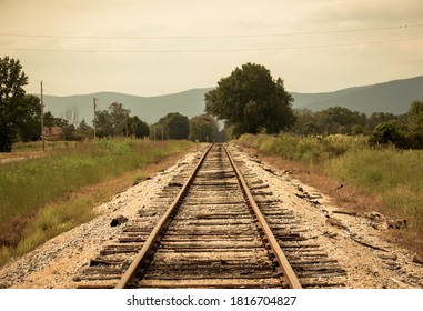 An Old Rail Road Track With Mountains In Background