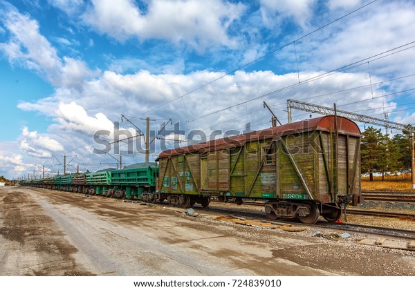 Old\
railway freight trains. Old rusty train station on a beautiful\
sunny day with amazing blue sky and white\
clouds.