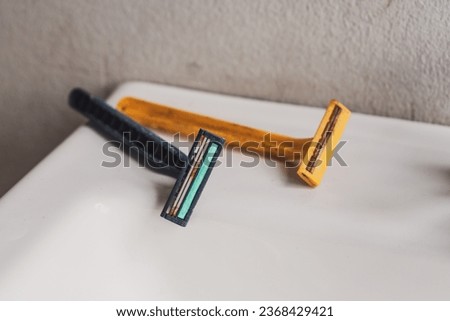 An old razor with a rusty blade that has been used before placed on the edge of the basin in the bathroom.