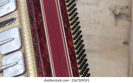 Old red accordion. Wind musical instrument. Old concertina. Musical orchestra instrument. Equipment that reproduces musical sounds.